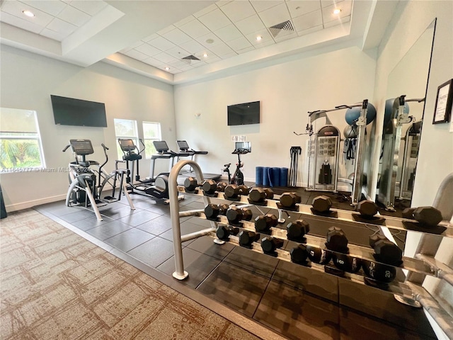 exercise room with visible vents, baseboards, and a raised ceiling