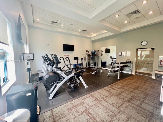 exercise room with recessed lighting, visible vents, a tray ceiling, and baseboards