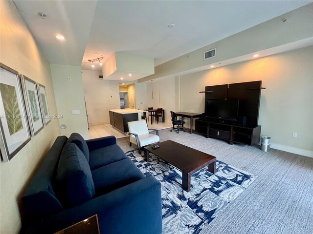 living area featuring visible vents, light colored carpet, and baseboards