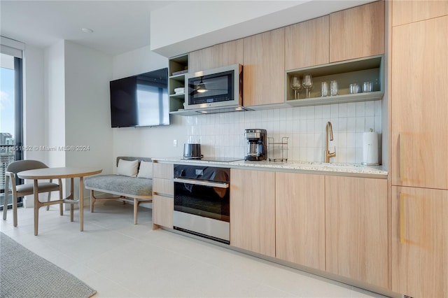 kitchen with stainless steel appliances, sink, light stone countertops, and light brown cabinetry