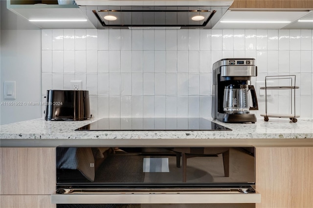 kitchen featuring light stone counters, light brown cabinets, and decorative backsplash