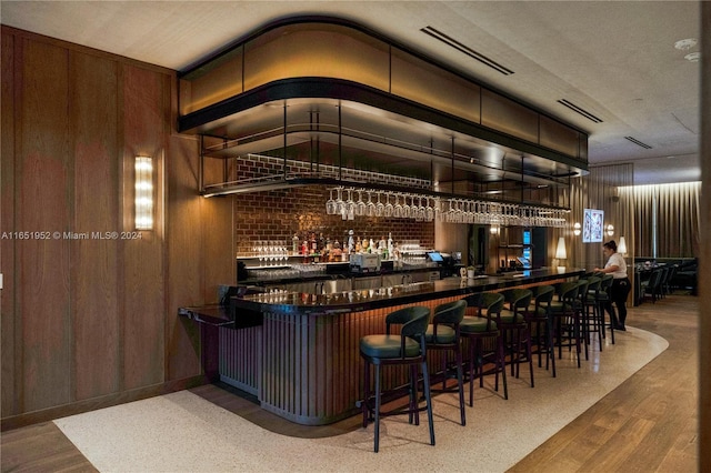 bar with wood-type flooring, brick wall, and wooden walls