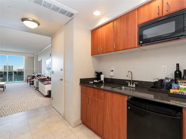 kitchen featuring a water view, black appliances, dark stone counters, and sink