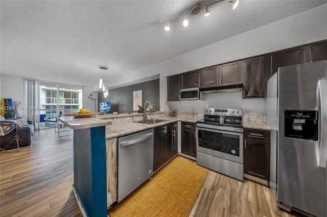 kitchen with stainless steel appliances, kitchen peninsula, a textured ceiling, and sink