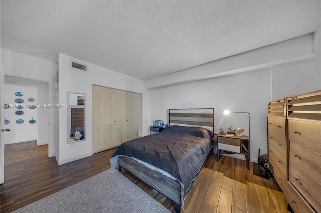 bedroom with a textured ceiling, dark hardwood / wood-style flooring, and a closet