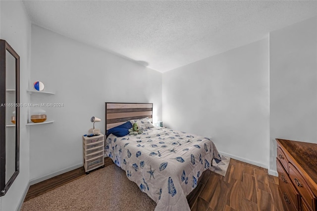 bedroom featuring a textured ceiling and dark hardwood / wood-style flooring