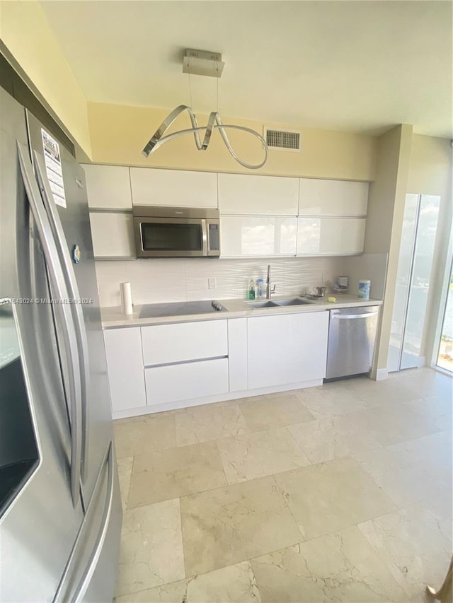 kitchen with pendant lighting, a notable chandelier, white cabinetry, decorative backsplash, and stainless steel appliances