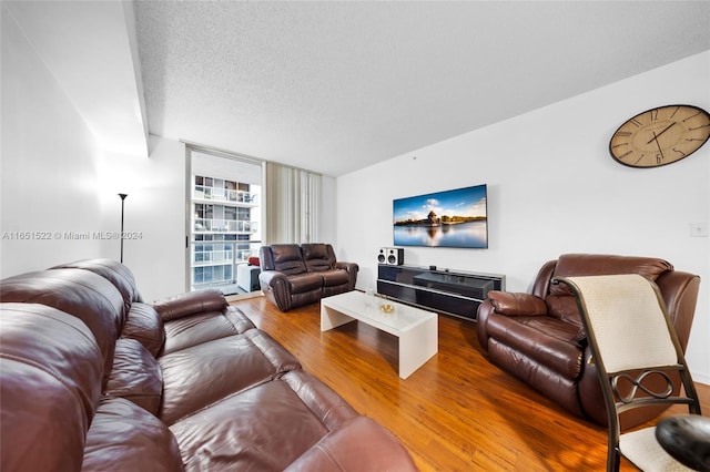 living room with a textured ceiling, floor to ceiling windows, and hardwood / wood-style floors