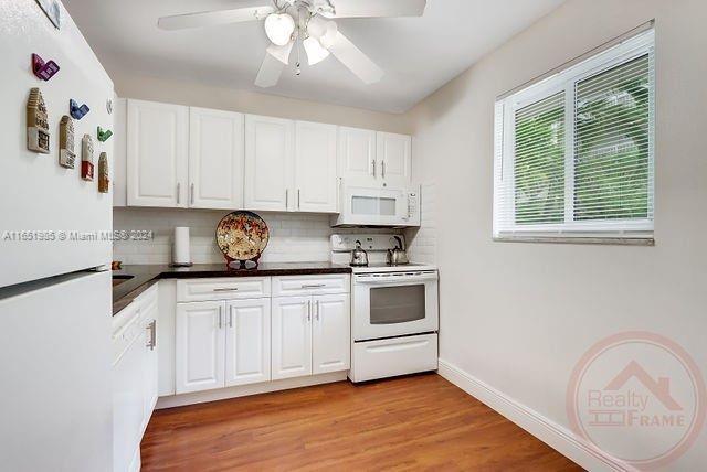 kitchen with white cabinetry, white appliances, light hardwood / wood-style flooring, tasteful backsplash, and ceiling fan