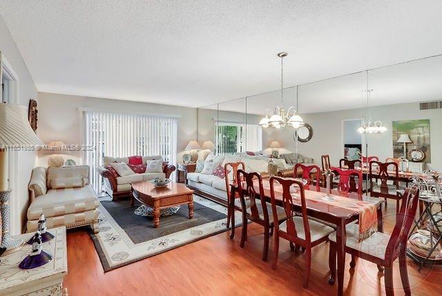 dining room featuring hardwood / wood-style flooring, an inviting chandelier, and a textured ceiling