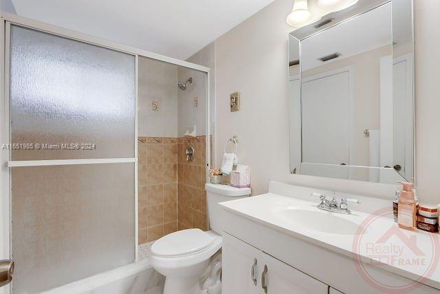 bathroom featuring walk in shower, toilet, and vanity