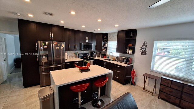 kitchen featuring backsplash, stainless steel appliances, sink, a kitchen island, and a breakfast bar