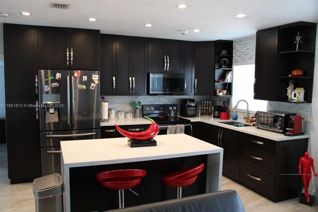 kitchen with stainless steel appliances, a kitchen island, sink, decorative backsplash, and a breakfast bar area