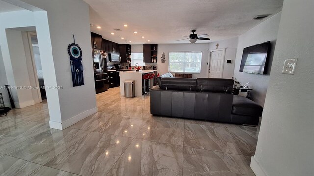 living room with a textured ceiling, ceiling fan, and sink