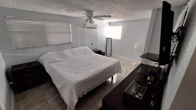 bedroom with a textured ceiling, ceiling fan, and a wall unit AC