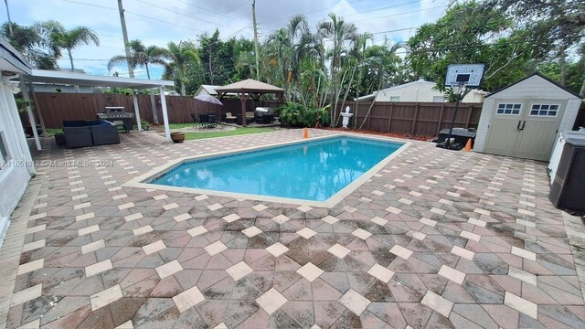 view of pool with a gazebo, grilling area, a shed, and a patio