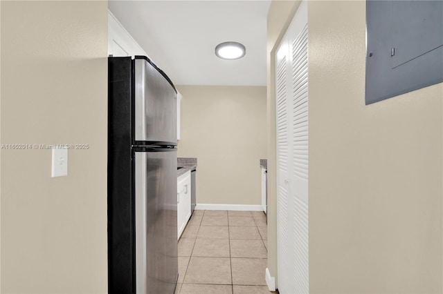 interior space with light tile patterned floors, electric panel, and stainless steel refrigerator