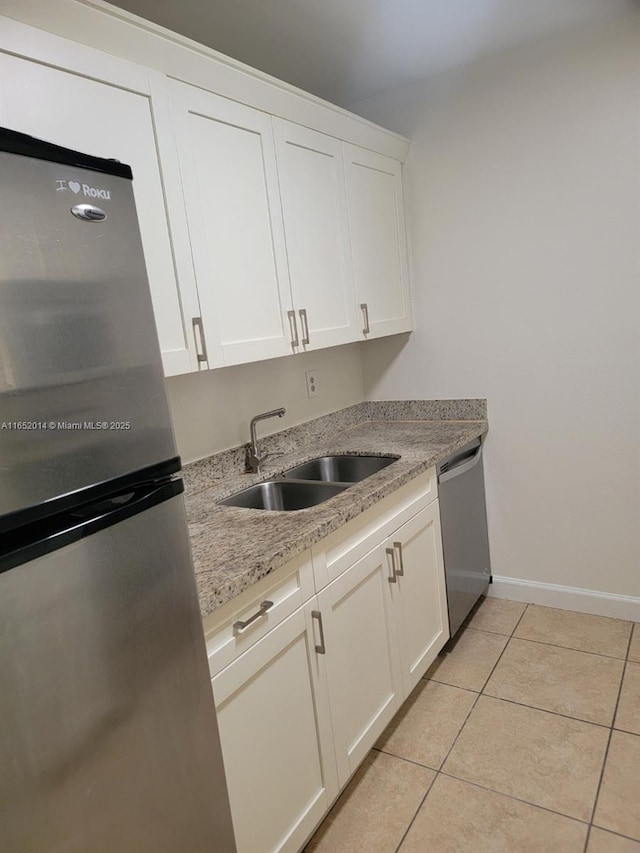 kitchen featuring light tile patterned floors, stainless steel appliances, white cabinetry, and sink