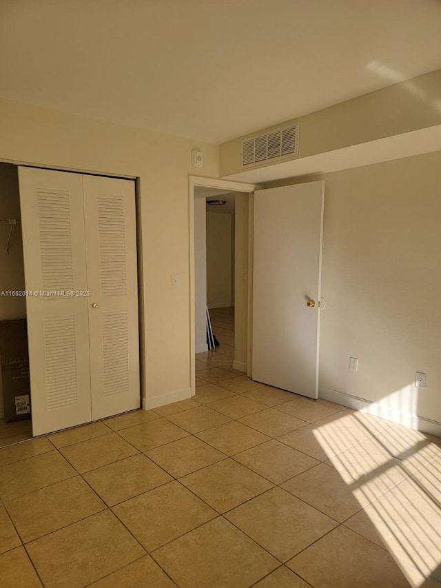 unfurnished bedroom with light tile patterned flooring and a closet