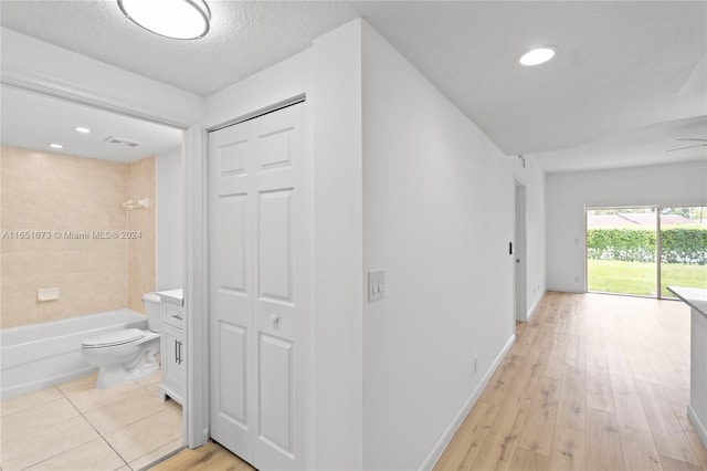 hall featuring a textured ceiling and light hardwood / wood-style floors