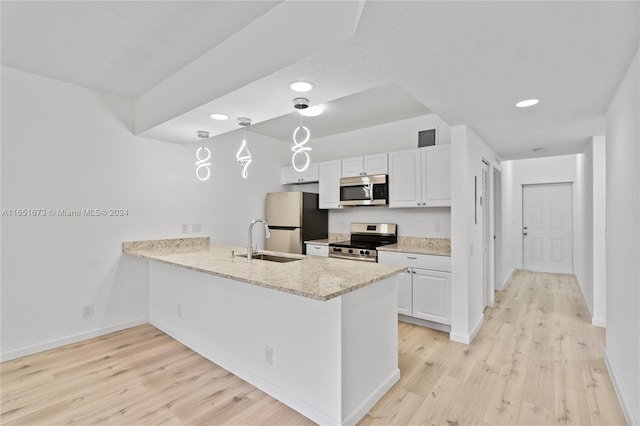 kitchen with light wood-type flooring, white cabinets, appliances with stainless steel finishes, and light stone counters