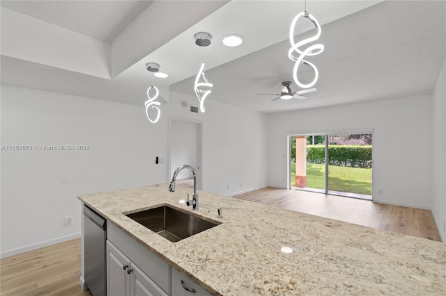 kitchen featuring sink, light stone countertops, decorative light fixtures, and light hardwood / wood-style floors