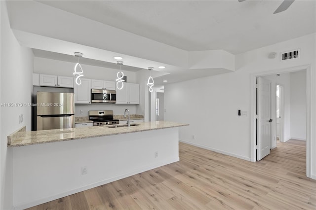 kitchen featuring stainless steel appliances, decorative light fixtures, white cabinetry, and light hardwood / wood-style floors