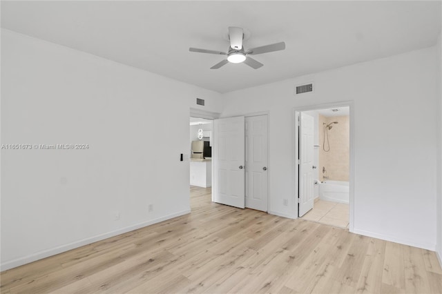 unfurnished bedroom featuring light wood-type flooring, stainless steel fridge, connected bathroom, ceiling fan, and a closet