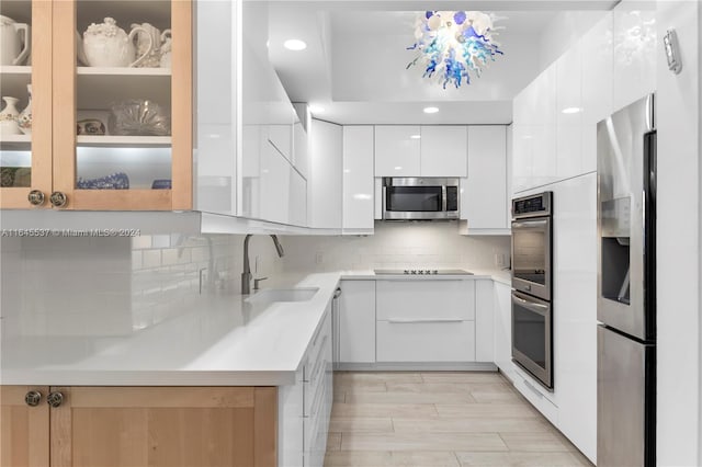 kitchen featuring light wood-type flooring, sink, decorative backsplash, appliances with stainless steel finishes, and white cabinets