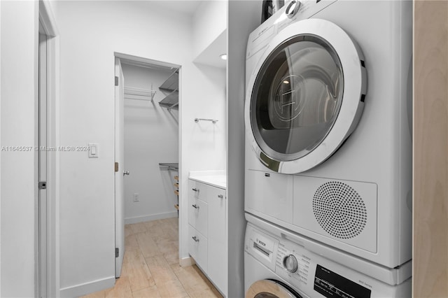 clothes washing area featuring light wood-type flooring and stacked washer and clothes dryer