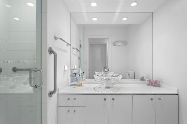 bathroom featuring a shower with shower door, toilet, and vanity