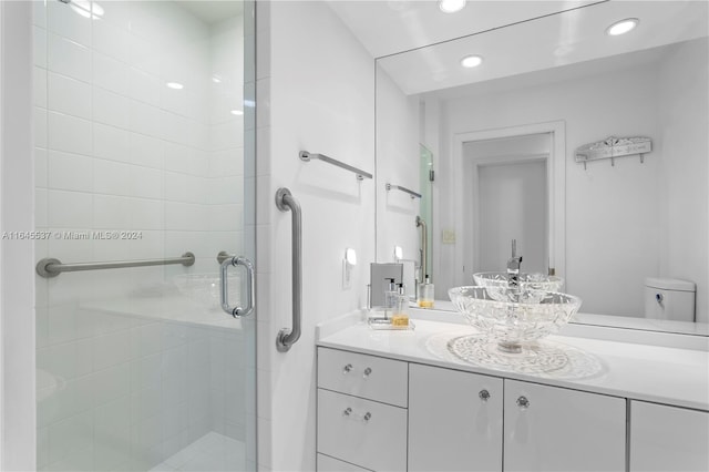 bathroom featuring vanity, a shower with shower door, and toilet