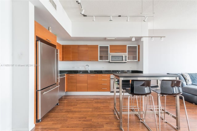 kitchen featuring hardwood / wood-style floors, stainless steel appliances, rail lighting, and a textured ceiling