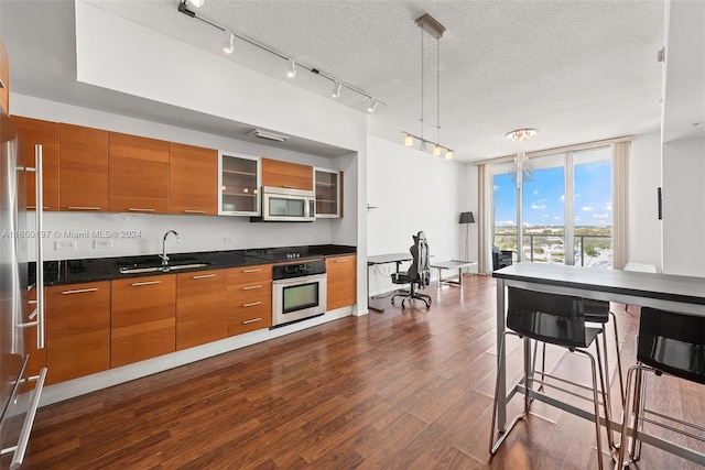 kitchen featuring a textured ceiling, dark hardwood / wood-style floors, decorative light fixtures, stainless steel appliances, and sink