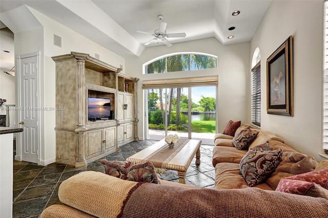 living room with ceiling fan, plenty of natural light, and vaulted ceiling