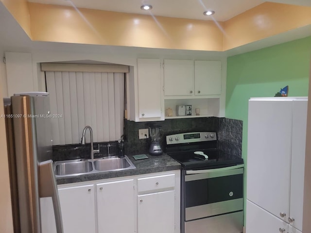 kitchen featuring tasteful backsplash, stainless steel appliances, sink, vaulted ceiling, and white cabinets