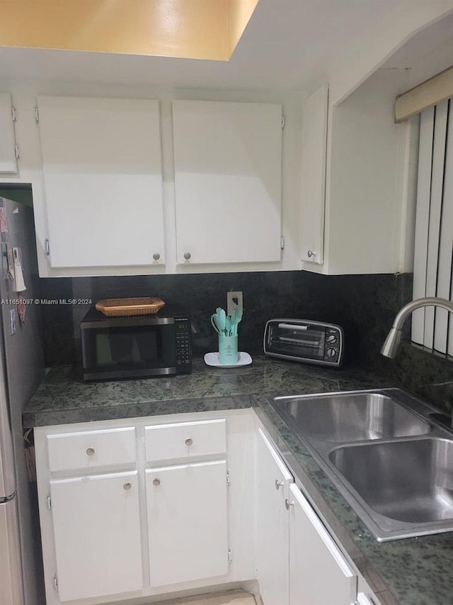 kitchen featuring backsplash, sink, appliances with stainless steel finishes, and white cabinets