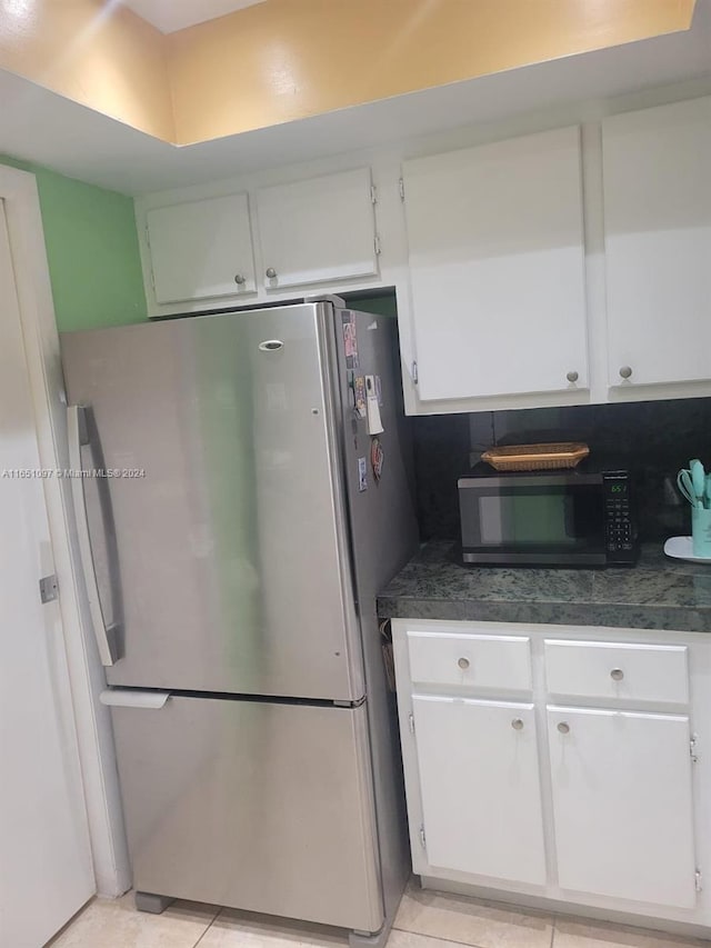 kitchen with white cabinets, light tile patterned floors, and stainless steel refrigerator