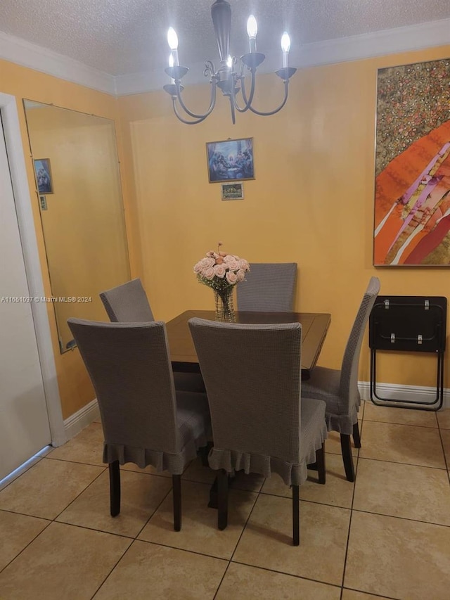 tiled dining room with a textured ceiling, ornamental molding, and an inviting chandelier