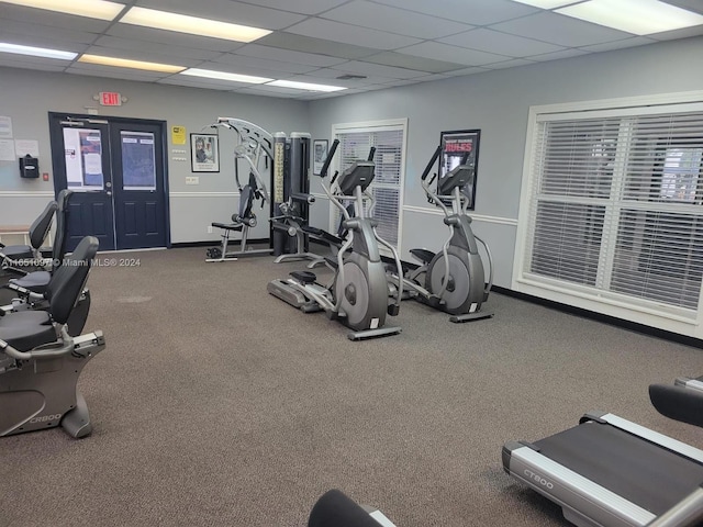 exercise room featuring a paneled ceiling and carpet floors