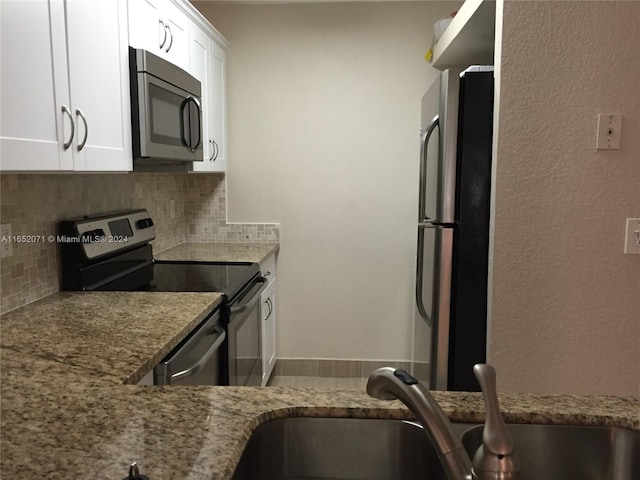 kitchen with stainless steel appliances, light stone counters, sink, decorative backsplash, and white cabinets