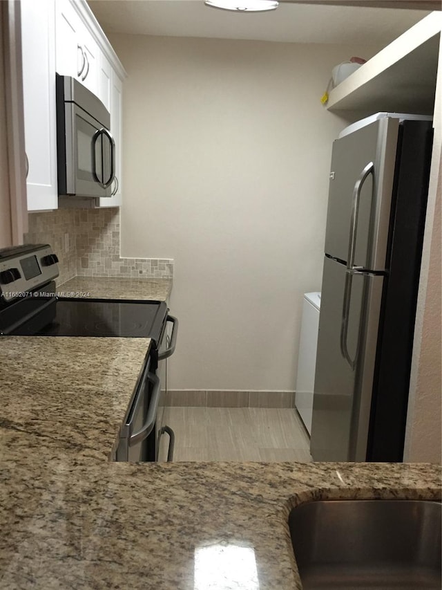 kitchen featuring tasteful backsplash, light stone counters, stainless steel appliances, and white cabinets