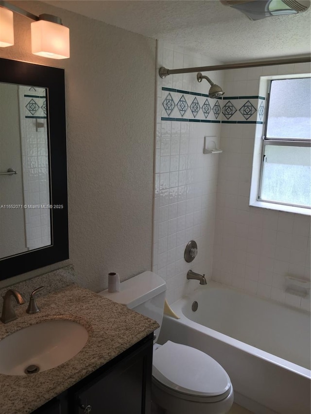 full bathroom featuring a textured wall, shower / bathing tub combination, vanity, and toilet