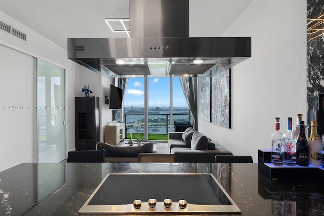 interior space with wall chimney range hood and black electric cooktop