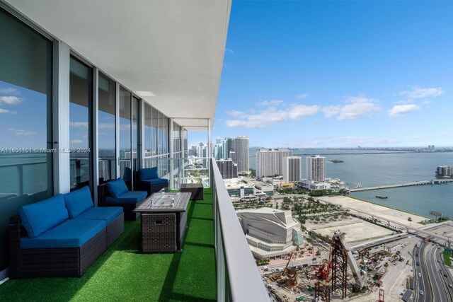 balcony featuring a water view and an outdoor living space with a fire pit