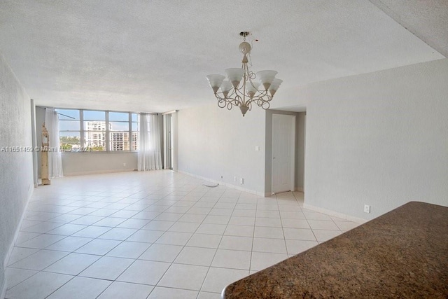 tiled empty room featuring a textured ceiling and an inviting chandelier