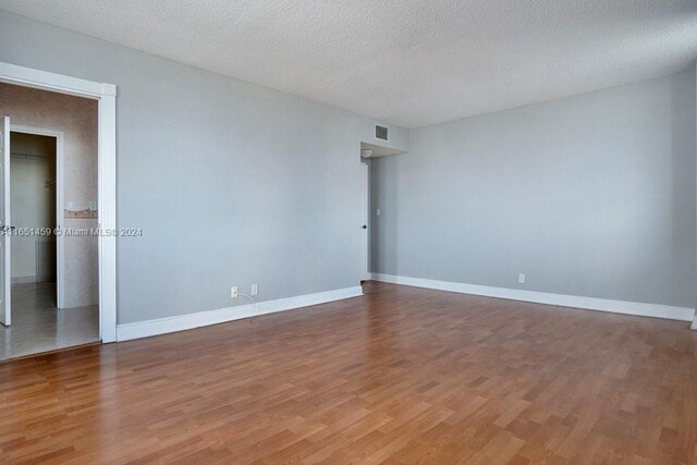 spare room featuring a textured ceiling and wood-type flooring