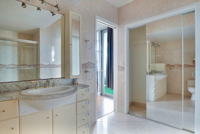 bathroom with tile patterned flooring, vanity, toilet, and a shower with shower door