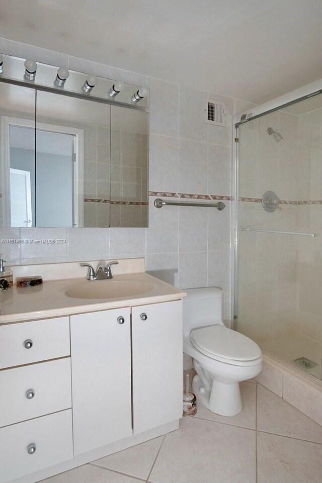 bathroom featuring vanity, an enclosed shower, tile walls, toilet, and tile patterned floors