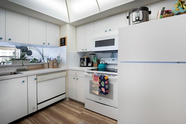 kitchen featuring white appliances, hardwood / wood-style flooring, sink, and white cabinets